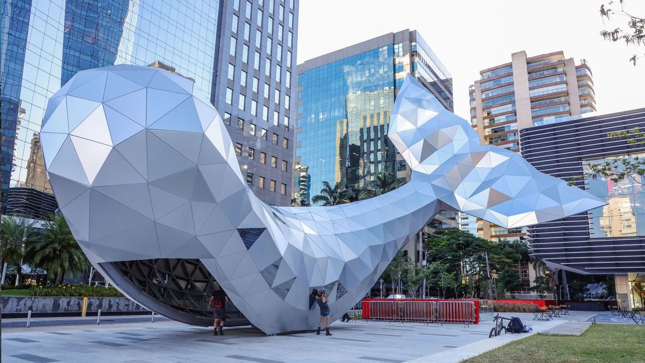 Escultura de baleia geométrica prateada diante dos edifícios corporativos da região da Avenida Faria Lima, em São Paulo