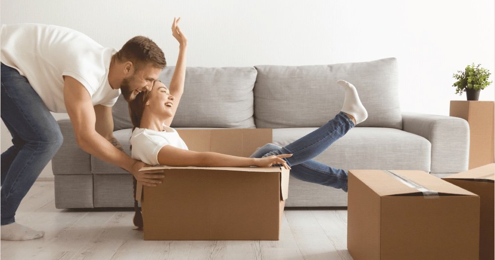 Casal brinca com caixas de mudança na sala do novo apartamento