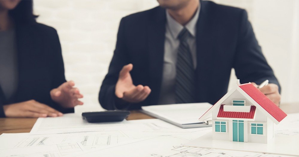 Reunião de negócios com miniatura de casa, calculadora e documentos sobre a mesa