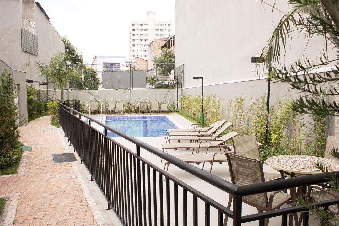 Foto do caminho de pedra até a piscina e o deck com espreguiçadeiras