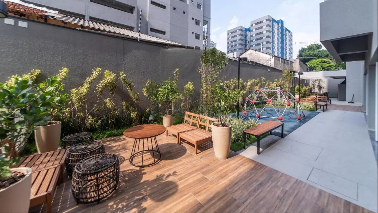Foto do jardim com deck de madeira, bancos e playground ao fundo