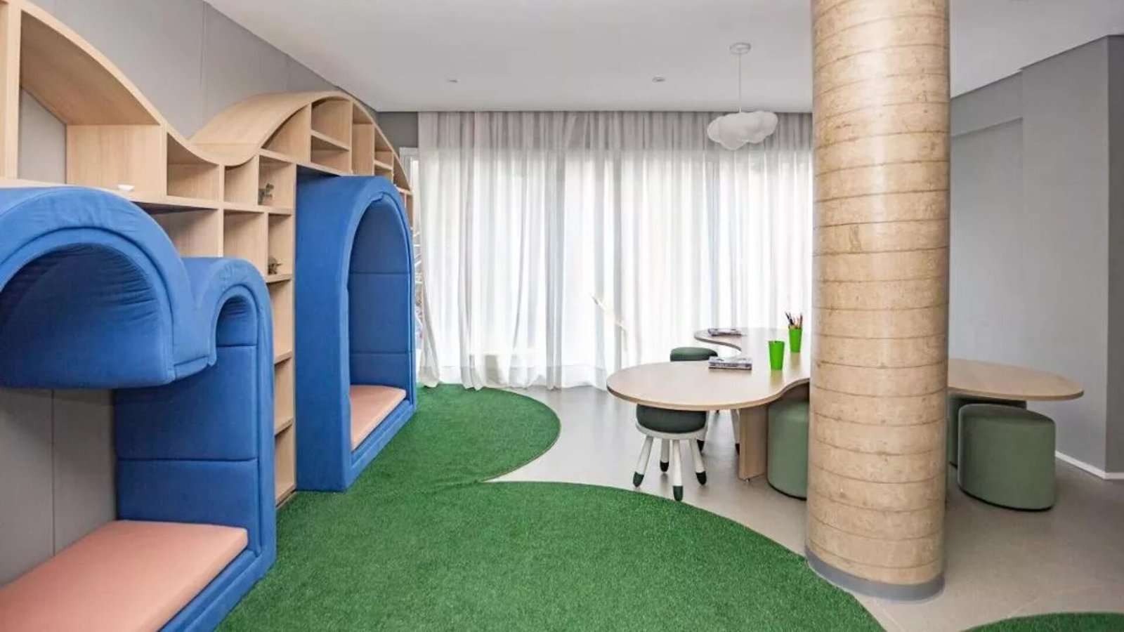 Foto da brinquedoteca com nichos coloridos, grama sintética e mesa infantil