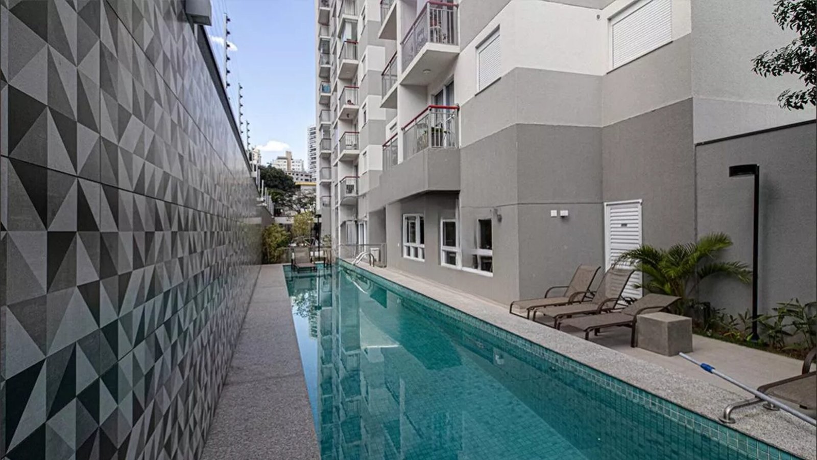 Foto da piscina de raia ao lado da torre do Bracon Ipiranga entregue, com a parede de revestimento geométrico