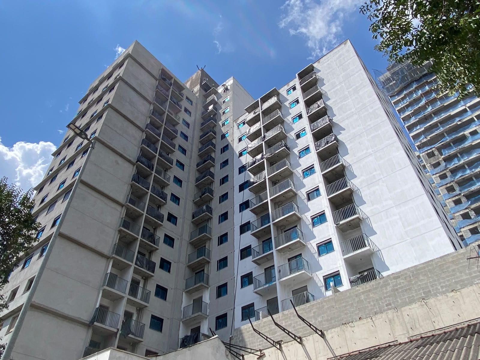 Foto da obra em 28 de setembro de 2026: fachada da torre vista de baixo, com os terraços das unidades
