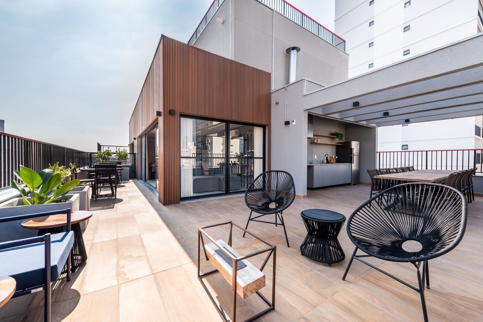 Foto do terraço do rooftop com churrasqueira, mesas e estares ao ar livre