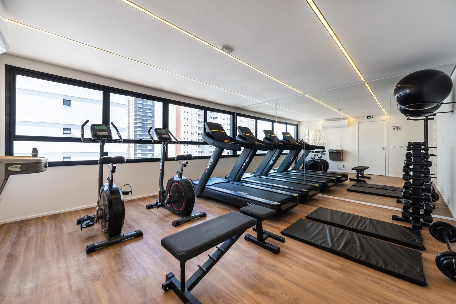 Foto do espaço fitness entregue, com esteiras, bicicleta e halteres